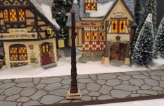 a street light sitting on the side of a road next to snow covered trees and buildings