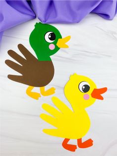 two paper ducks and one duckling on a bed