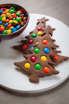 two decorated cookies sitting on top of a white plate next to a bowl of candy