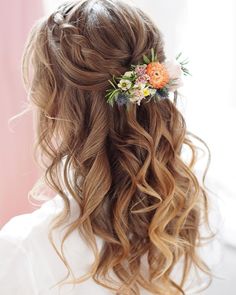 the back of a woman's head with long hair and flowers in her hair