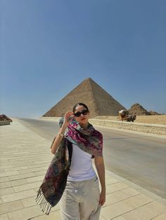 a woman is standing in front of the pyramids