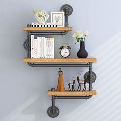 two metal shelves with books, vases and other items on them against a blue wall