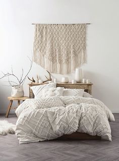 a bed with white comforter and pillows in a room next to a wooden table