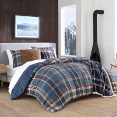 a bed with plaid comforter and pillows in a room