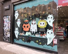 a store front window with halloween decorations on display in the window and cats painted on it