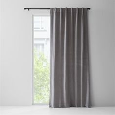 an open window with a gray curtain hanging on it's side and a white wall in the background