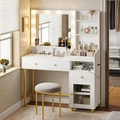 a white vanity with gold legs and drawers in a bedroom next to a window,