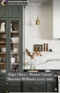 a kitchen with green cabinets and marble counter tops, gold accents on the top shelf