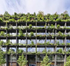 an office building with plants growing on the side of it's windows and balconies