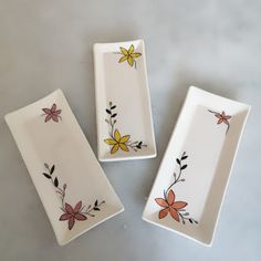 three white dishes with flowers painted on them