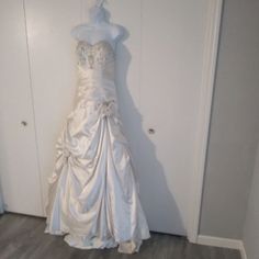 a white wedding dress hanging up against a wall