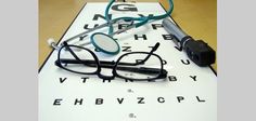 eyeglasses and glasses laying on top of an eye chart