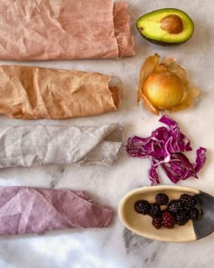 an assortment of fruits and vegetables are laid out on a marble counter top with paper