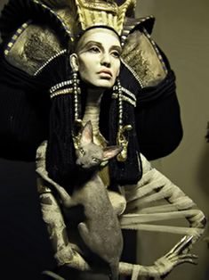 a statue of an egyptian woman holding a cat in her arms and wearing a headdress