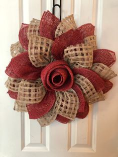 a red and tan burlocked wreath hanging on a door