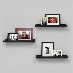 three black shelves with pictures and frames on them