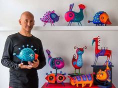 a man standing in front of a table with some colorful sculptures on top of it