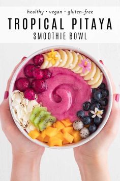 a person holding a bowl filled with smoothie bowls topped with fruits and veggies