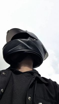 a person wearing a black jacket with a helmet on their head and the sky in the background