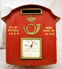 a red post box with a clock on the front and two dials at the top