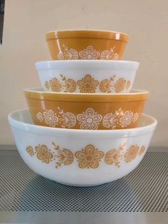 three yellow and white bowls are stacked on top of each other in the same pattern