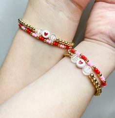 two bracelets that have hearts and beads on them, one has a red bead