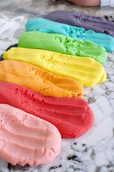 there are five different colored ice creams on the marble counter top, and one is half eaten