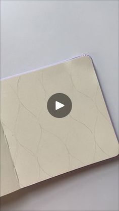 an open book with a video play button on the front and back cover in grey