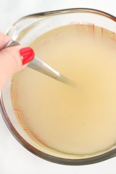 a person is using a knife to mix ingredients in a glass bowl with a measuring spoon