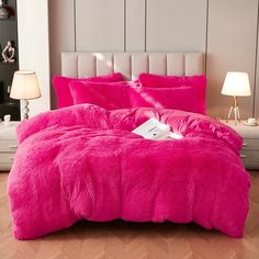 a bright pink comforter and pillows on a bed