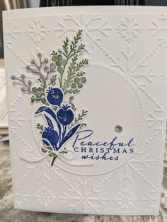 a white card with blue and green flowers on it, the words peaceful christmas makes