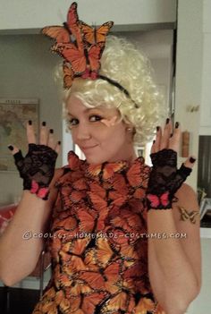 a woman with white hair and butterfly wings on her head, wearing an orange dress