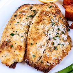 two pieces of chicken on a plate with asparagus and potatoes