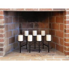 four candles are placed in front of a brick fireplace