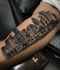 a man's arm with a city skyline tattoo on it