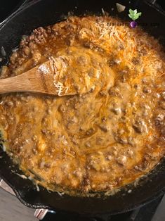 a skillet with some food cooking in it and a wooden spoon on the side