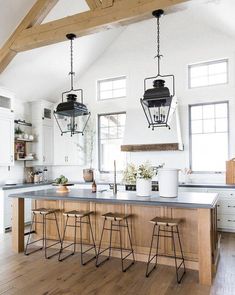 a kitchen island with stools and lights hanging from it's ceiling over the counter