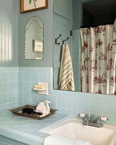 a bathroom with blue tiles and a white sink in front of a mirror that is hanging on the wall