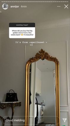 a gold mirror sitting on top of a table next to a black bag and purse