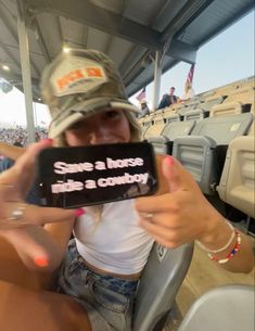 a woman sitting in the stands holding up a cell phone