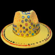 Description: Stand out at your next festival with this stunning handcrafted yellow fedora, embellished with vibrant 3D circular designs. Each piece is uniquely designed to react to UV light, making it the perfect accessory for night parties, Burning Man, and other rave events. This custom art hat was meticulously created by Ilgaz Kuren, blending artistic expression with festival fashion. With its eclectic mix of colors and detailed accents, this hat adds a pop of flair to any outfit. Features: U Rave Hats, Circular Designs, Festival Mode, Night Parties, Mix Of Colors, Uv Reactive, Artistic Expression, Uv Light, Burning Man