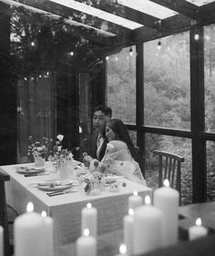 a man and woman sitting at a table with candles in front of them on their wedding day