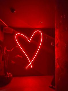 a red heart shaped neon sign in a dark room