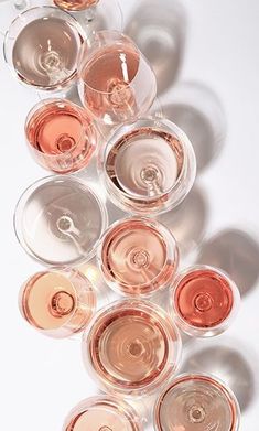 wine glasses filled with different types of wines on a white surface, arranged in the shape of a pyramid