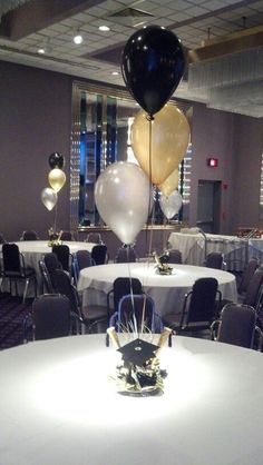 some balloons are hanging from the ceiling in a banquet hall with tables and chairs set up for an event