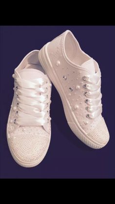 two white shoes with pearls on them sitting next to each other in front of a blue background