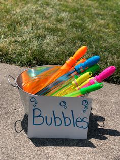 a bucket filled with lots of different colored pens sitting on top of a cement slab