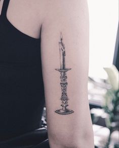 a woman with a tattoo on her arm holding a knife in one hand and a candle in the other