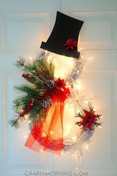 an image of a christmas wreath with lights on it and a hat hanging from the front door