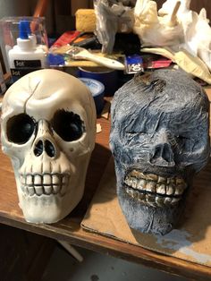 two fake skulls sitting on top of a wooden table